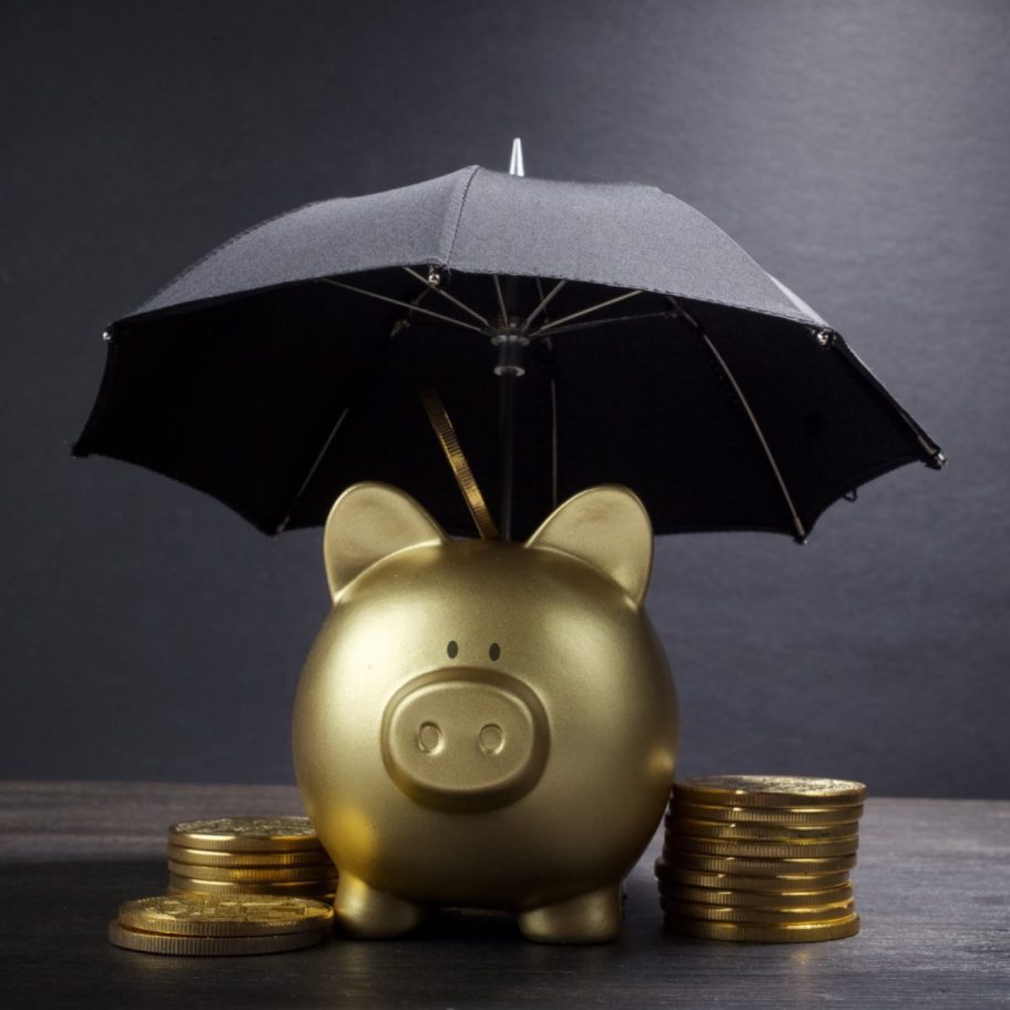 goldenes Sparschwein mit Münzen und Regenschirm